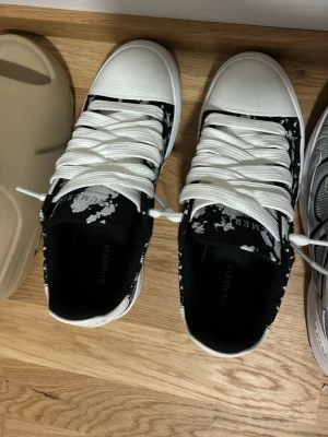 HELT NYA Svarta och vita sneakers från numeris - Snygga sneakers från NUMERUS i svart och vitt med coolt splattermönster. Skorna har vita snören, rund tå och är låga i modellen. Ovandelen är i textil och syntet, perfekt för dig som vill sticka ut med din stil.
