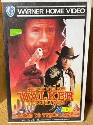 Walker Texas Ranger VHS Road to Vengeance - VHS-film med titeln 'Walker Texas Ranger: Road to Vengeance' från Warner Home Video. Omslaget har röd och gul färg med actionmotiv och cowboytema. Klassisk actionfilm med westernkänsla och polistema.