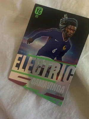 Samlarbild Electric Camavinga - Säljer en samlarbild från serien Top Class med motiv av fotbollsspelaren Camavinga i Frankrikes landslagströja. Kortet har texten 'ELECTRIC' i silver och grönt samt spelarstatistik på baksidan. Perfekt för dig som gillar fotboll och samlarkort.
