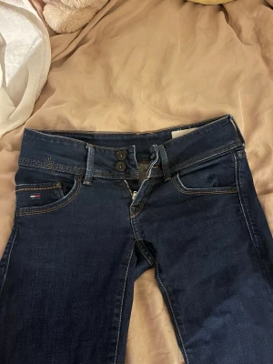 Lågmidjade bootcut jeans - Snygga mörkblå lågmidjade bootcut jeans med dubbla knappar i midjan. Storlek S från Tommy Hilfiger 
