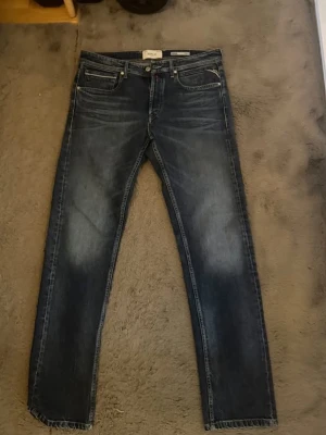 Mörkblå jeans från Replay - Snygga mörkblå jeans från Replay med klassisk femficksdesign och raka ben. Jeansen har subtila slitningar och kontrastsömmar. Jeansen är helt oanvända, priset kan diskuteras. 