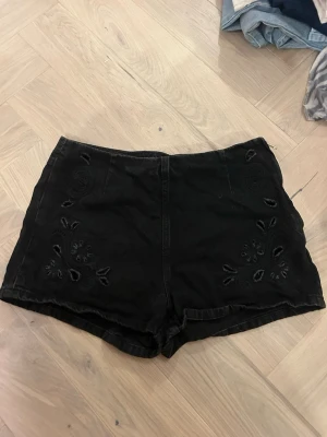 Svarta broderade shorts - Snygga svarta shorts med broderade blommor framtill. De har hög midja och är gjorda i ett mjukt bomullsmaterial. Perfekta för sommarens alla äventyr och ger en chill vibe till din outfit.