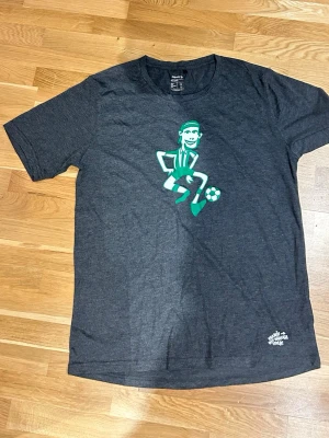 Mörkgrå t-shirt med fotbollstryck - Snygg mörkgrå t-shirt från Unisport med Hammarby tema. Passar perfekt för alla Hammarby fans.