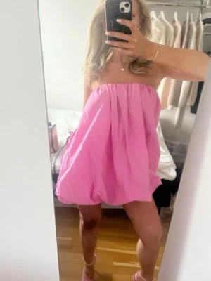 Axelbandslös rosa kortklänning - Säljer en superfin axelbandslös rosa kortklänning. Klänningen är köpt på Sellpy och är i ett mycket bra skick utan några defekter. Klänningen är från Zara i storlek S
