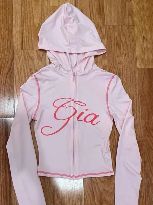Rosa loungewear-set från I.AM.GIA - Ljusrosa loungewear-set från I.AM.GIA med matchande hoodie och byxor. Hoodien har dragkedja, huva och rosa sömmar samt texten 'Gia' framtill. Byxorna har samma rosa sömmar och texten 'I.AM.GIA' baktill. Mjukt och stretchigt material. Stl M, i nyskick!🌸
