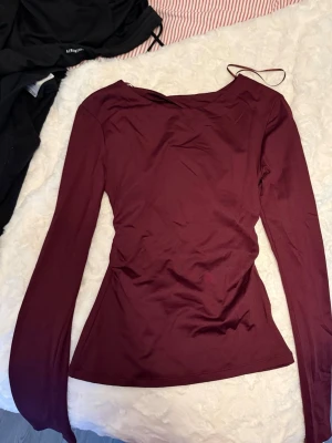 Vinröd långärmad topp med öppen rygg - Säljer en vinröd långärmad topp med en snygg öppen rygg och tight passform. Använd 2 gånger 