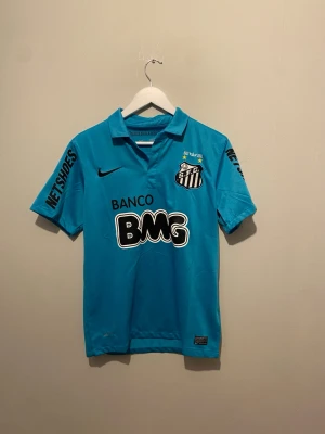 Blå Santos FC matchtröja från Nike - Säljer en blå Santos FC matchtröja från Nike med klubbmärke och sponsorloggor på bröstet och pikékrage och är tillverkad i ett lätt, ventilerande material. Perfekt för fotbollsträning eller att bära till vardags. Och även neymar på ryggen. 