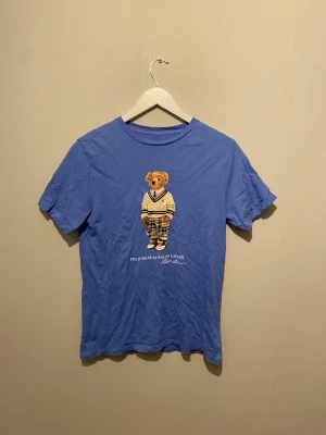 Blå Polo Bear t-shirt Ralph Lauren - Blå t-shirt från Ralph T-shirten har rund hals och korta ärmar, perfekt för en avslappnad och cool stil. Tröjan är i barn storlek och är 14-16 år