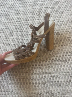 Bruna platåsandaler från Bianco - Säljer ett par bruna sandaler från Bianco med höga klackar i kork och dekorativa remmar med synliga sömmar. 