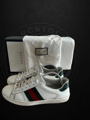 Gucci vita sneakers med gröna och röda ränder - !Tvättade och ser helt nya ut!Klassiska vita sneakers från Gucci med gröna och röda ränder på sidan och gröna detaljer vid hälen. Skorna har snörning och är tillverkade i skinn. Perfekta för dig som vill ha en ikonisk och stilren sneaker med lyxig känsla. ‼️JAG SKULLE KUNNA TÄNKA MIG ATT SÄNKA PRISET NÅGRA HUNDRALAPPAR ‼️🔝
