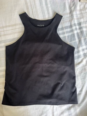 Svart linnetopp från H&M Move - Snygg svart linnetopp från H&M Move med hög halsringning och ärmlös design. Perfekt för en sportig look eller att styla till vardags. Tillverkad i mjukt och stretchigt material som sitter bekvämt mot kroppen.