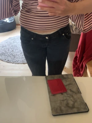 Svarta bootcut jeans med låg midja - Säljer ett par svarta bootcut jeans med låg midja från lager 157. Storlek M, längden i benen är långa fast om jag har långa ben. Tyget har blivit förstört som syns på bilden, troligen i tvätten. Säljer för jag ej använder dom. 