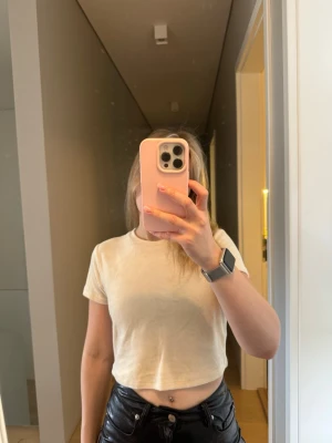 Gul croppad t-shirt från Monki - En enkel och stilren beige croppad t-shirt från Monki. T-shirten har rund halsringning och korta ärmar. Sammet material på utsidan.
