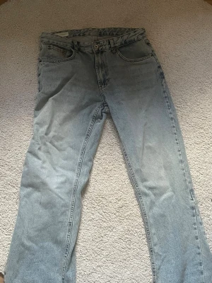 Ljusblå raka jeans - Säljer ett par ljusblå jeans med rak passform och klassisk femficksdesign. Jeansen har hög midja och är tillverkade i denim med en lätt tvättad look. Perfekta för en avslappnad och trendig stil. Flared