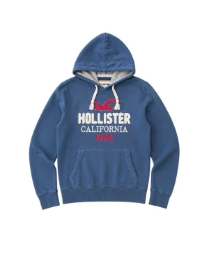 Blå hoodie från Hollister - Blå hoodie från Hollister med broderad logga och texten 'Hollister California 1922' på bröstet. Hoodien har vit dragsko, känguruficka och mjukt material på insidan. Detaljer i vitt och rött ger en klassisk collegekänsla.