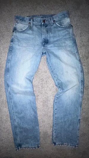 Ljusblå Wangler jeans, cowboy cut - Säljer ett par klassiska Wrangler 13MWZ Cowboy Cut Original Fit i en snygg ljus vintage-tvätt. Jeansen har en vintagekänsla med slitningar och tydliga sömmar på bakfickorna. Perfekta för en avslappnad och trendig look. Funkar till både boots och sneakers. Storlek är W30 L32. Passar mig bra som är 186cm och väger ca 65-70 kg.