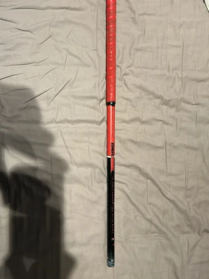 Zone innebandyklubba röd/svart - Säljer en Zone innebandyklubba i rött och svart med texten 'The Candy Edition' på skaftet. Klubban har ett greppvänligt handtag med lindat rött grepp och svart nedre del. Perfekt för dig som gillar innebandy och vill ha en snygg klubba. 