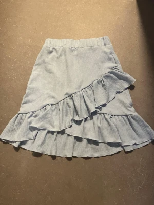 Ljusblå volangkjol från NLY Trend - Supersöt ljusblå kjol från NLY Trend i kort modell med bred resår i midjan och dubbla volangdetaljer framtill. 