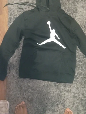Jordan svart loungewear set - Säljer ett svart loungewear set från Jordan med den klassiska Jumpman-loggan i vitt på både hoodie och byxor. Hoodien har huva med dragsko och magficka, byxorna har resår i midjan och smalare benslut. Perfekt för chill dagar hemma eller till träningen.