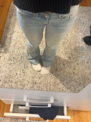 Ljusblå bootcut jeans - Säljer ett par ljusblå bootcut jeans med klassisk femficksdesign och låg midja. Jeansen har en lätt utsvängd passform nertill och är tillverkade i denim med lite stretch för extra komfort. Perfekta för en avslappnad och trendig look.