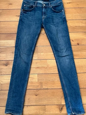 Tiger of Sweden jeans - Snygga blå slim fit jeans med klassisk femficksdesign och normalhög midja. Jeansen har en mörk tvätt och raka ben, perfekta till en avslappnad stil. Materialet är denim i bomull med lite stretch för extra komfort.