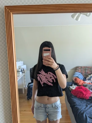 Svart croppad t-shirt med rosa tryck - Säljer en svart cool t-shirt med rosa detaljer. Då den ej kommer till användning.. Köpt i Kina i en affär som heter mo xie och upplevs som xs eller s