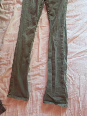 Gröna bootcut jeans från True Religion - Snygga gröna jeans från True Religion med bootcut passform och unika bakfickor med lock och knapp. Klassisk femficksmodell och detaljerad söm. Perfekta för dig som vill sticka ut med en cool vintage vibe.
