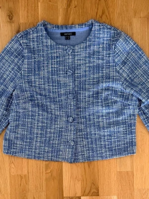 Elegant tweedjacka från Esmara – blå/vit, stl 40 - Superfin och elegant tweedjacka från Esmara i storlek 40. Klassisk kortare modell i blått och vitt med vävd struktur och skimrande detaljer som ger en väldigt exklusiv och chic look. 17% bomull.   Jackan har dekorativa klädda knappar framtill och en tidlös design som passar perfekt både till jeans, kjol eller mer uppklädda outfits.  Mjuk och bekväm med lätt stretch i tyget. Väldigt fin kvalitet och snygg passform.  