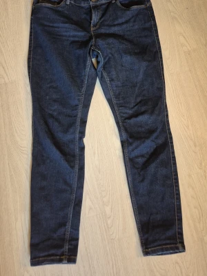 Mörkblå slim fit jeans storlek L/30 - Snygga mörkblå slim fit jeans med klassisk femficksdesign och kontrastsömmar. Jeansen har normal midja och raka ben. Från Vero möda storlek L/30. Katt finns I hemmet
