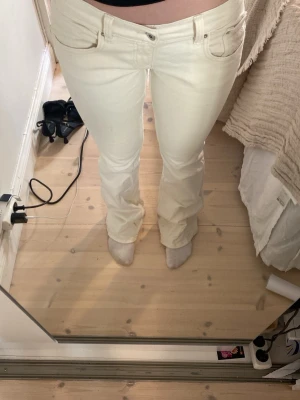 Vita bootcut jeans med broderi - Säljer ett par vita bootcut jeans med snyggt broderi på bakfickorna. Jeansen har klassisk femficksmodell, normal midja och är tillverkade i ett stretchigt denimtyg för skön passform. Perfekta för dig som vill ha en clean och fräsch look. Dem är lite fläckiga och slitna nertill. 