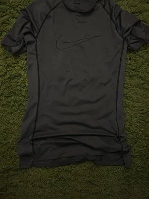 Svart Nike Pro Dri-FIT träningströja - Svart kortärmad träningströja från Nike Pro med Dri-FIT-teknologi och tight fit. Tröjan har diskret Nike-logga på bröstet och är tillverkad i ett lätt och ventilerande material som passar perfekt för intensiva träningspass.