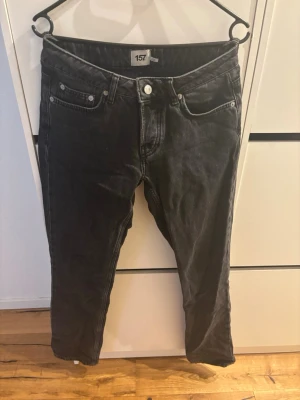 Svarta jeans från 157 - Ett par svarta jeans från 157 med klassisk femficksdesign och knappgylf. Jeansen har en något smalare passform och är tillverkade i denim. Perfekta för dig som gillar en enkel och stilren look.