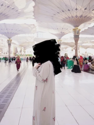 Beige klänning med broderade blommor - Lång beige klänning med v-ringning och dragkedja framtill. Klänningen har vida ärmar och är dekorerad med små broderade blommor i rosa och grönt. Perfekt för dig som gillar en elegant och modest stil.