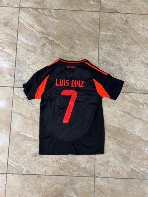 Colombia fotbollskit Luis Diaz #7 - Snyggt svart och rött fotbollskit med tröja och shorts, inspirerat av Colombias landslag. Tröjan har Luis Diaz och nummer 7 tryckt på ryggen samt ett emblem på bröstet. Tillverkad i lätt och ventilerande material, perfekt för träning eller match.