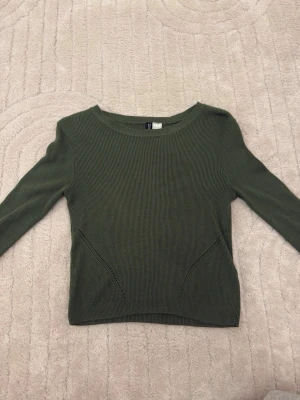 Olivgrön  tröja - Säljer en olivgrön tröja med rund halsringning och diskreta ribbade detaljer. Tröjan har långa ärmar och en enkel, stilren design som passar perfekt till jeans eller kjol. 