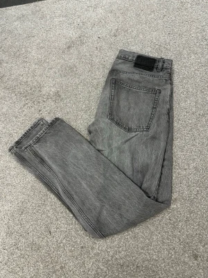 Gråa jeans från Lager 157 - Säljer ett par grå tvättade jeans med rak passform och klassisk femficksdesign. Stolen width 30 och length 32. Jeansen har en svart patch bak i midjan och är tillverkade i ett slitstarkt denimtyg. Perfekta för en avslappnad och trendig look.  Skriv över det minsta lilla eller över den minsta funderingen!🔥🔥