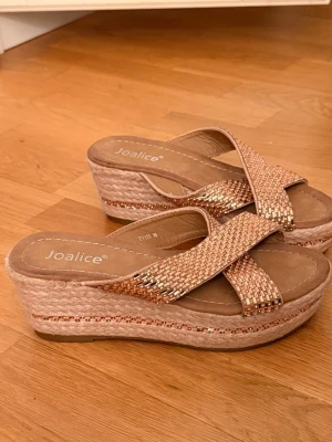 Roséguldiga platåsandaler från Joalice - Snygga platåsandaler från Joalice i roséguld med korslagda remmar täckta av små glittrande pärlor. Storlek 36. Inprincip oanvända 