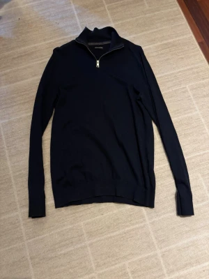 Mörkblå stickad halvzip-tröja - Snygg mörkblå stickad tröja från Jack&Jones med halvzip och hög krage. Tröjan har långa ärmar och ribbade muddar vid ärmslut och nederkant. Perfekt till lager på lager och enkel att matcha med olika outfits. PRISET KAN DISKUTERAS