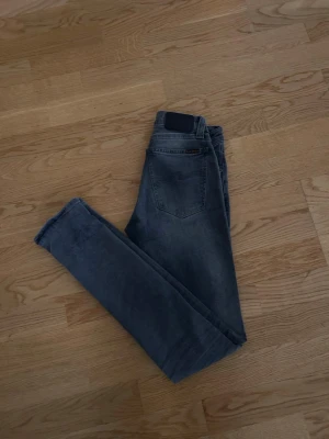 Nudie jeans W25 L32 - Säljer ett par riktigt snygga jeans från Nudie i en fin grå färg. Jeansen är i mycket bra skick. Storleken är W25 L32. Säljes så billigt då jag bara vill få bort dom.