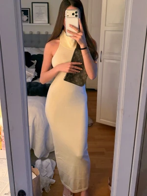 Beige långklänning med halterneck - Snygg beige långklänning med halterneck och figurnära passform. 