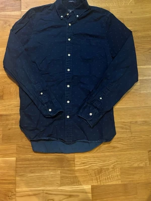 Mörkblå skjorta från Gant - Stilren mörkblå skjorta från Gant med diskret mönster och vita knappar🔥 Storlek M 😊📏 Fraktar inom 1-2 dagar💨📦 Hör av er vid frågor eller funderingar!😊