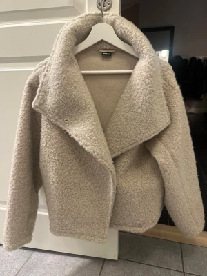 Beige teddyjacka med hög krage - Jag säljer en teddyjacka i beige från Gina tricot i storlek XS som har använts ett väldigt fåtal gånger. Tyvär så har knappen i mitten ramlat av från jackan💕