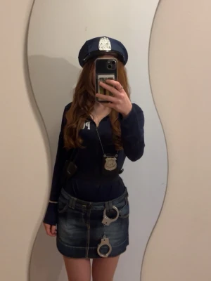 Polisdräkt med accessoarer - Säljer en komplett polisdräkt för maskerad eller cosplay. Inkluderar mörkblå skjorta med shorts, , polis-keps, , polisbricka, walkie-talkie och svarta remmar. Perfekt för temafest eller halloween!