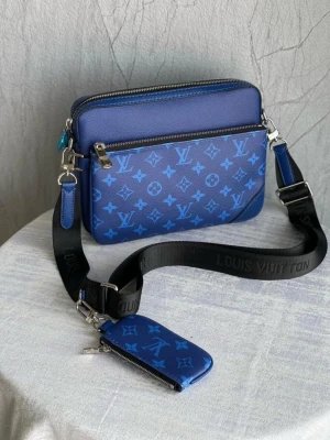 Blå axelväska från Louis Vuitton - Snygg blå axelväska från Louis Vuitton med klassiskt monogrammönster i ljusblått. Väskan har en justerbar svart axelrem med Louis Vuitton-tryck och en matchande liten blå accessoar med dragkedja. Tillverkad i läder och har flera fack med dragkedja. Priset kan diskuteras vid snabb affär!