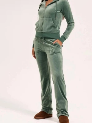 Grönt Juicy Couture sett - Setet består av en zip-hoodie med fickor och matchande byxor med fickor. Båda delarna har diskret Juicy Couture-logga broderad. Perfekt för chill dagar hemma. Storlek, S i tröja och Xs i byxor