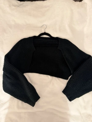 Svart cropped stickad bolero - Säljer en svart, ribbstickad bolero med lång ärm och croppad passform.