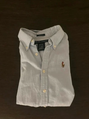 Ljusblå skjorta från Ralph Lauren - Klassisk ljusblå skjorta från Ralph Lauren. Storlek S slim fit men sitter som xs. Finns lite defekter på skjortan som på bilderna.