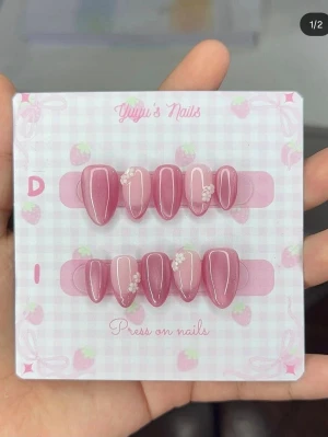 Rosa press-on naglar med pärldekor - Säljer ett set press-on naglar i glansig rosa nyans . Naglarna har en almondform och är dekorerade med små vita pärlor och blommor för en söt och trendig look. Perfekt för dig som vill ha snygga naglar snabbt och enkelt.