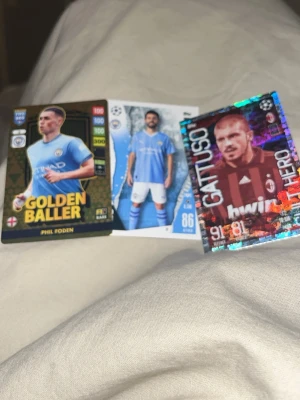 Fotbollssamlarkort Golden Baller - Säljer tre fotbollssamlarkort från FIFA 365-serien, inklusive ett Golden Baller-kort med guldiga detaljer och två andra kort med holografiska och färgstarka motiv. Perfekt för samlare som gillar fotboll och unika kort.