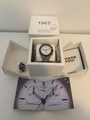Omega x Swatch Speedmaster Moonswatch - Säljer en Omega x Swatch Speedmaster Moonswatch med vit urtavla och grå boett. Klockan har klassisk kronografdesign, tydliga svarta markeringar. Snygg och ikonisk accessoar för dig som gillar stilrena detaljer.